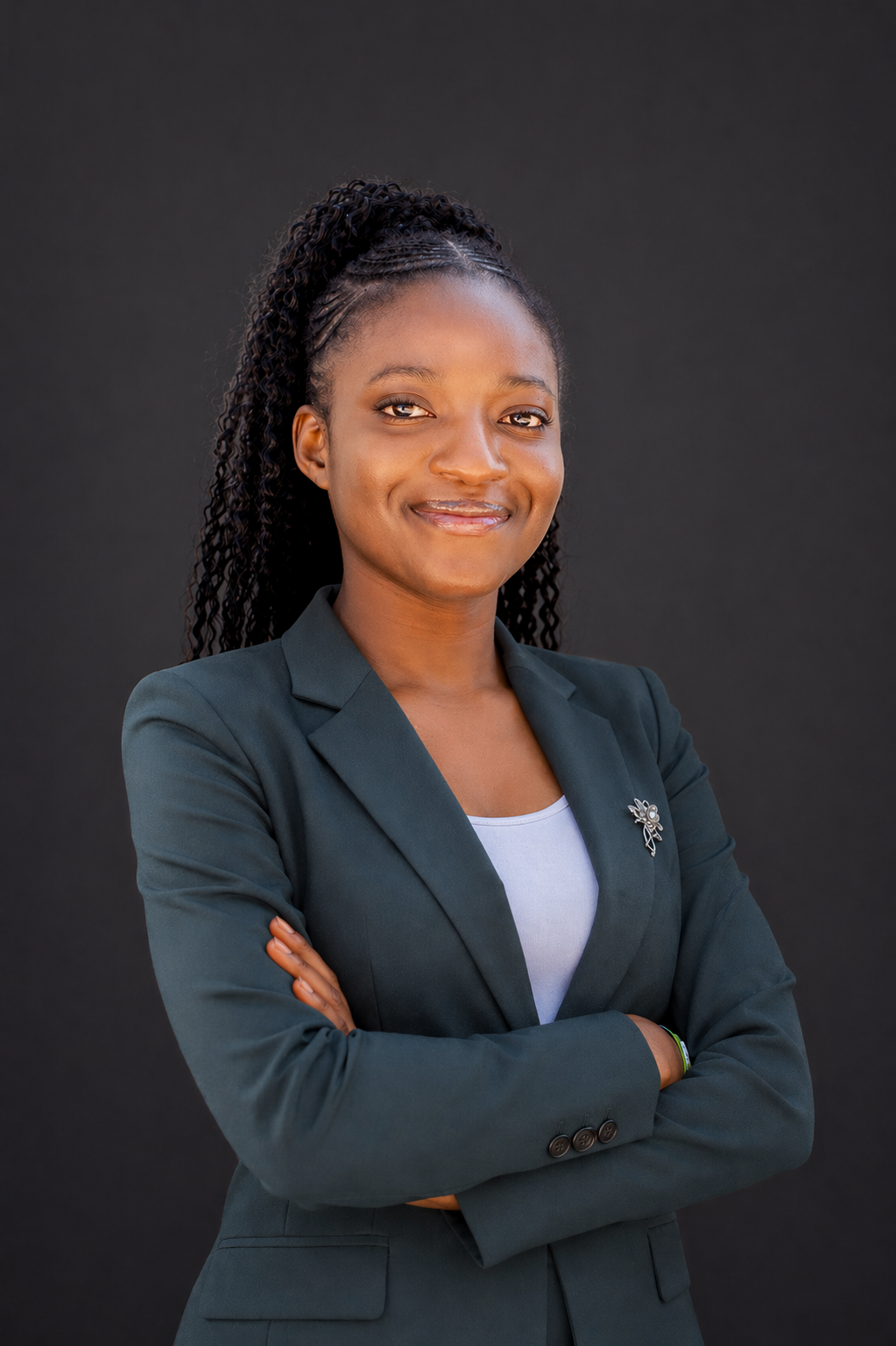 Alicia smiling with her arms crossed, wearing a dark blazer.